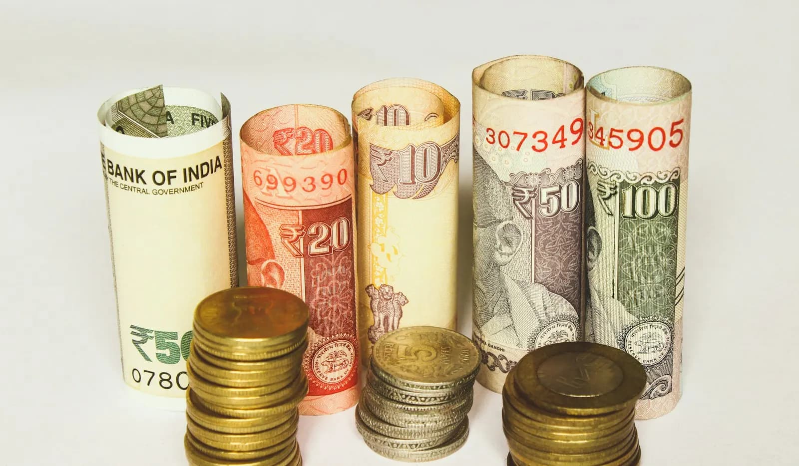 Rolled Indian rupee notes and stacks of coins